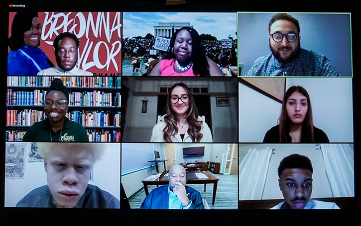 Mason students and President Washington appear on a screen together during a panel discussion at the Evening of Reflection