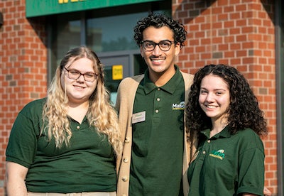 three students in green shirts outside
