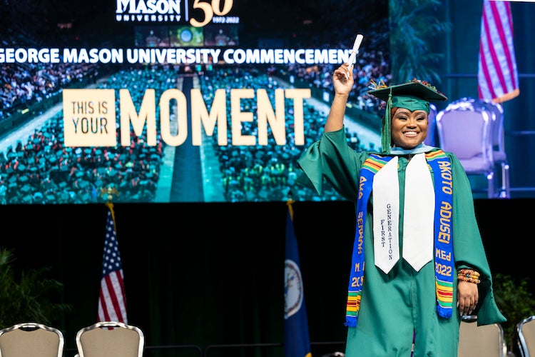 graduate on stage holding a scroll
