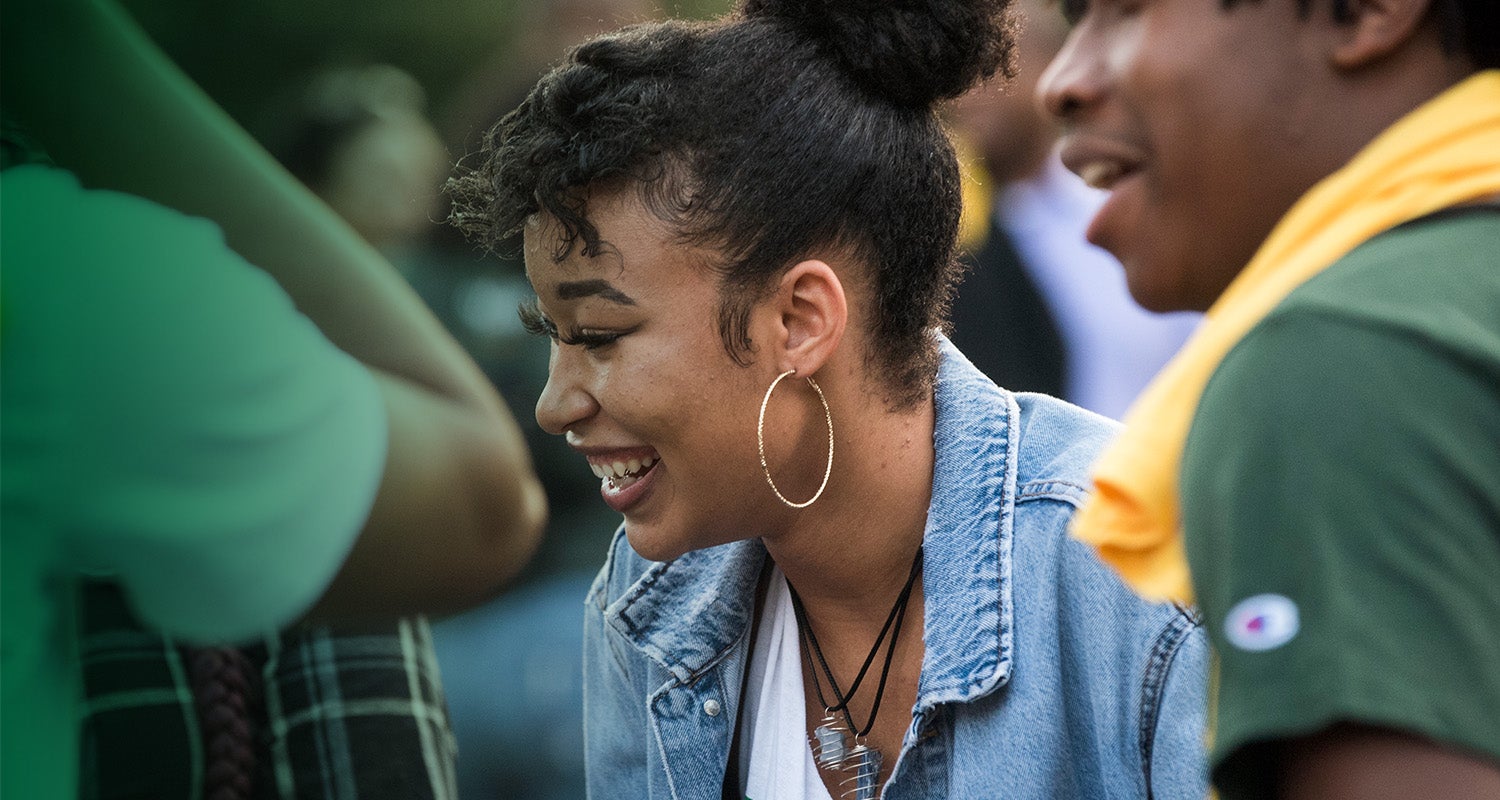 A Mason student smiles and laughs outside on campus
