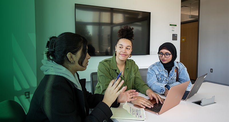 A trio of Mason students collaborate in a a classroom in Horizon Hall