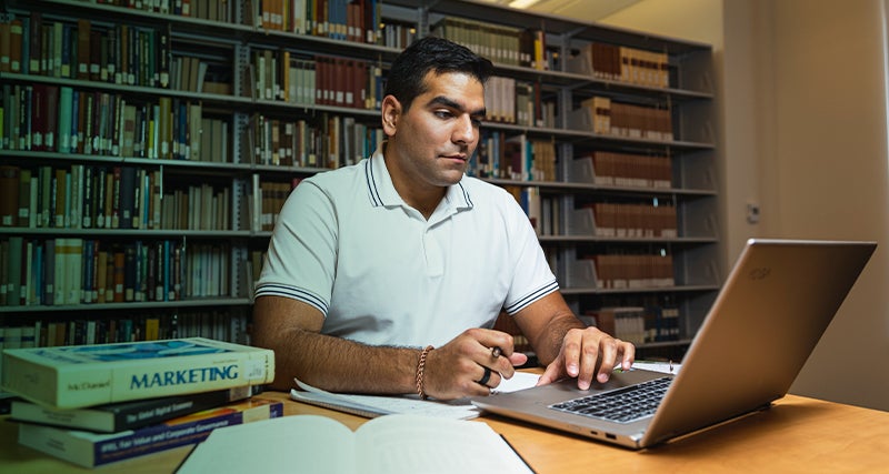 A student works diligently at a table in the library
