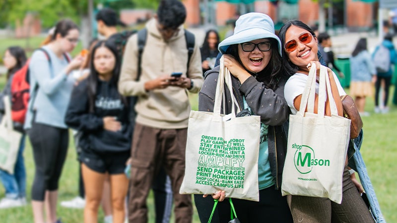A pair of Mason students brandish shopMason bags at during AMPLIFY.