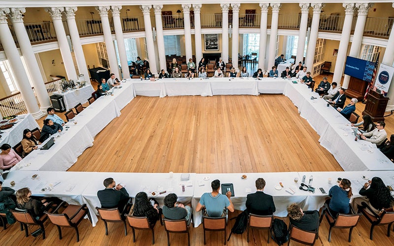 People sit at tables forming a very large square.