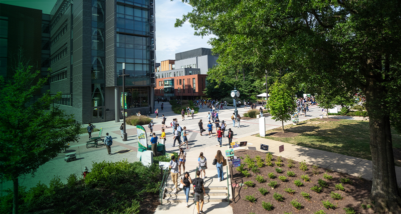 Students walk across the Fairfax Campus in-between classes, with Horizon Hall and Fenwick Library in the background.