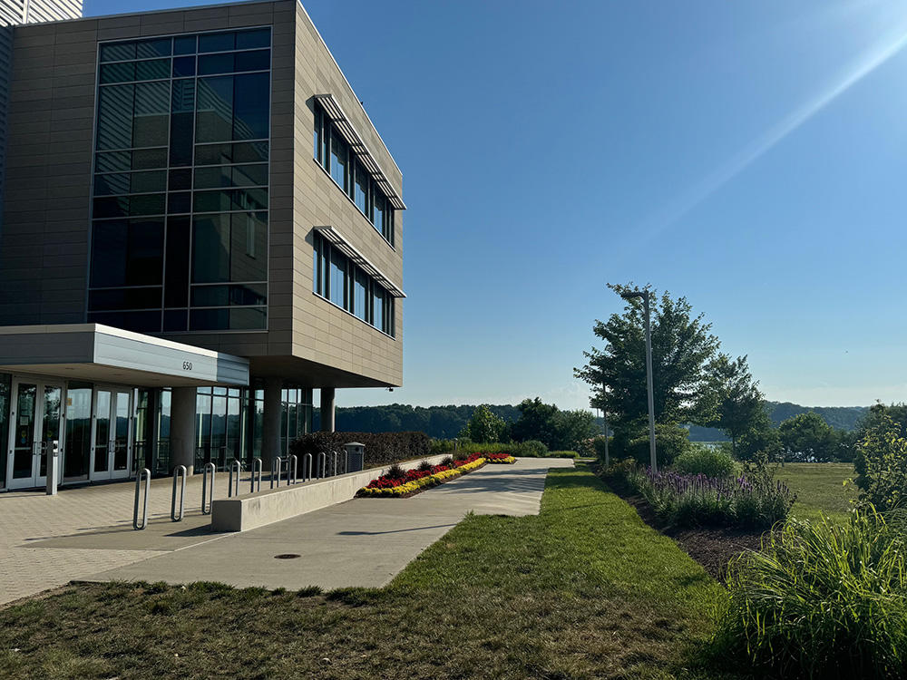 The exterior of the Potomac Science Center, including a building entrance and a view of the Potomac River mostly obstructed by greenery.