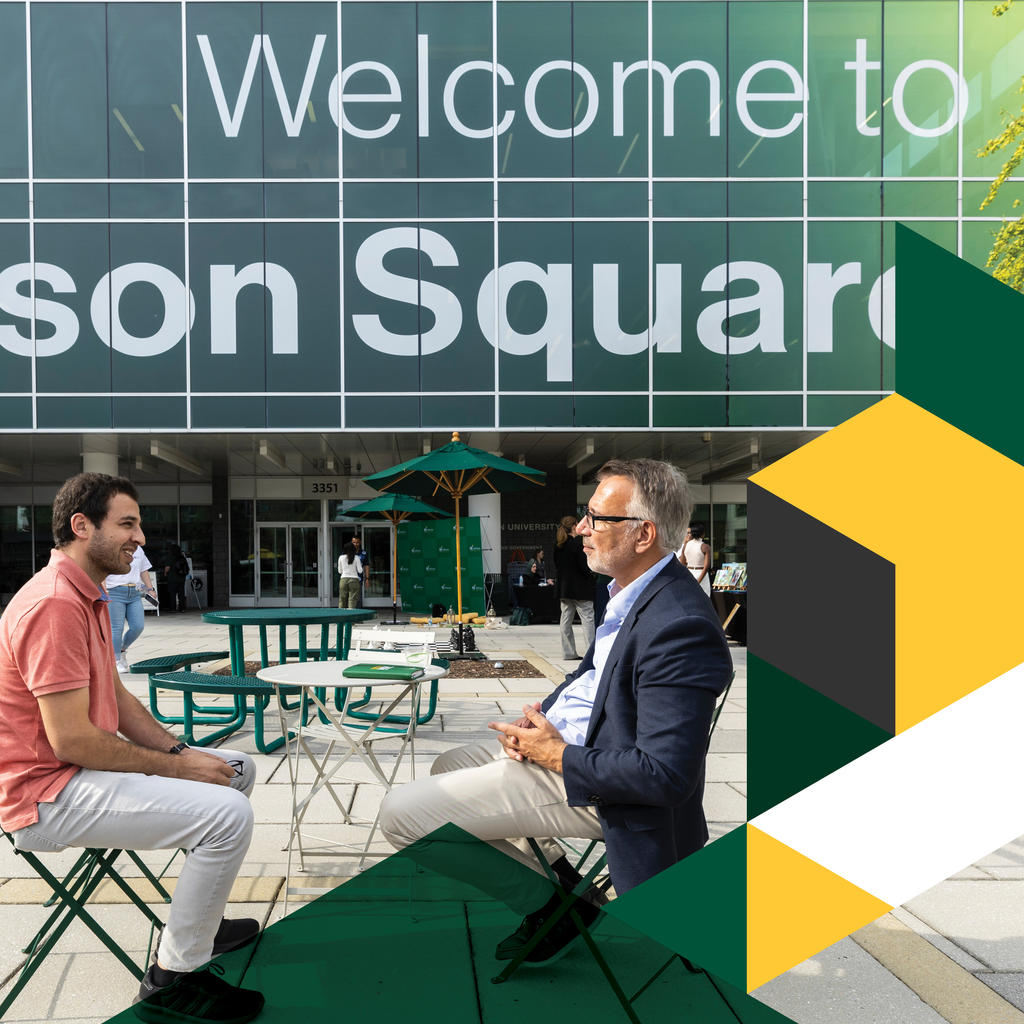 Dean of the Carter School sits at a table outside of Mason Square talking with a student