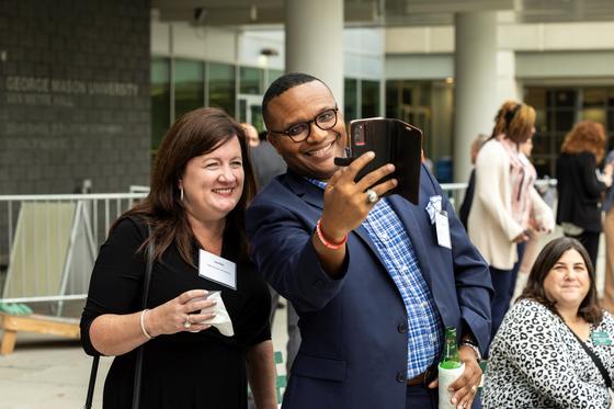 A group of people take a selfie together on the plaza at Mason Square 